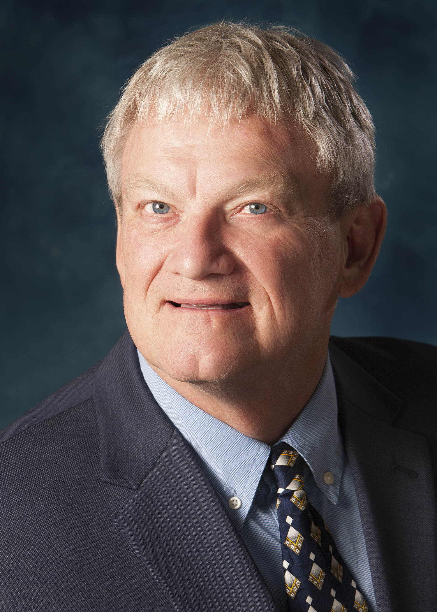 Headshot of a man wearing a tie and suit jacket